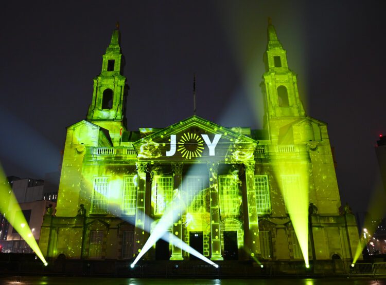 `Leeds Town Hall is lit yellow with the JOY logo revealed.