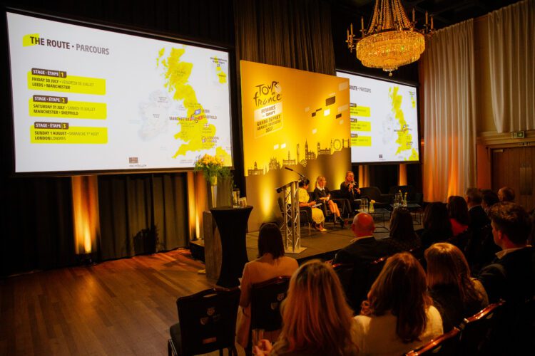 The Tour de France Femmes avec Zwift routes are presented on large screens at an event.