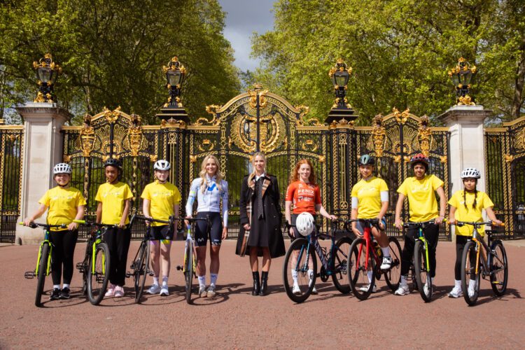Young riders join Race Director Marion Rousse and professionals outside Canada Gate in London.